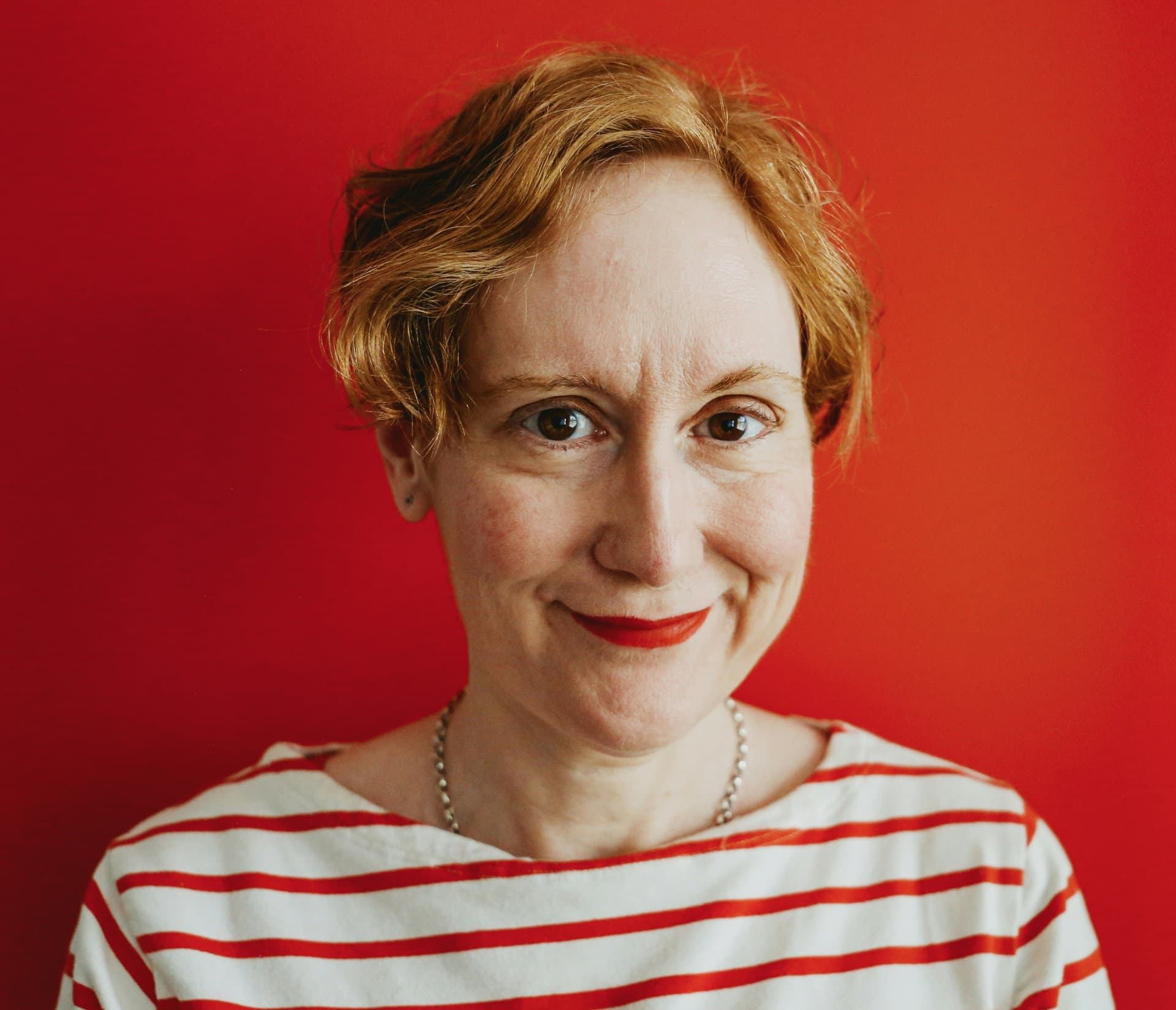 Person in a striped shirt against a red background.